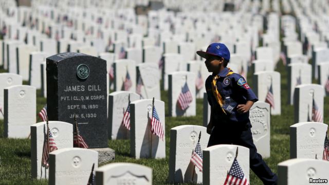 Một hướng đạo sinh Mỹ đặt cắm các lá quốc kỳ Mỹ tại các ngôi mộ trong nghĩa trang Quốc gia Cypress Hills, ở Brooklyn, New York, 23/5/15